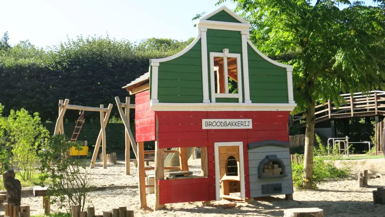 Parque infantil en Holanda con casita de panadería, columpios y tobogán. Ideal para que los niños jueguen y se diviertan.