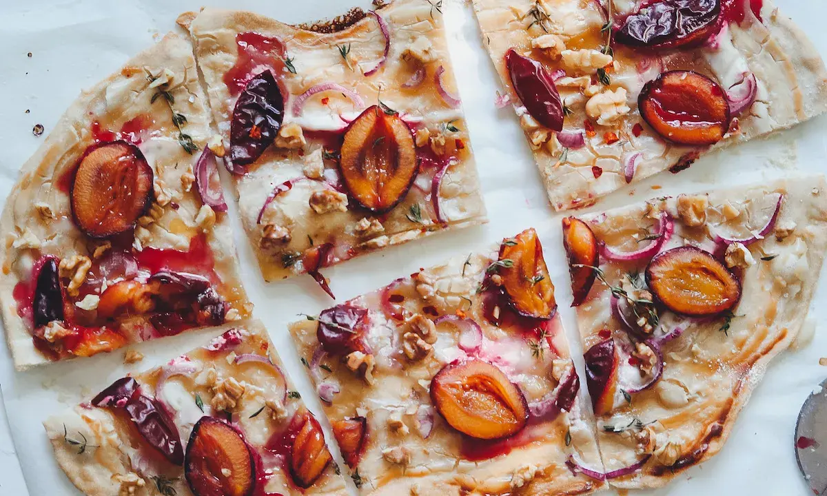 Flammkuchen mit Pflaumen, Zwiebeln und Walnüssen. Ein köstlicher Flammkuchen Belag, der süß und herzhaft kombiniert.