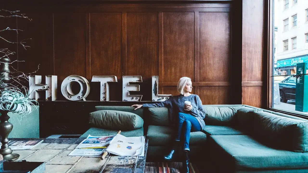 Kobieta siedzi na kanapie w hotelu, zastanawiając się, ile zarabia technik hotelarstwa.