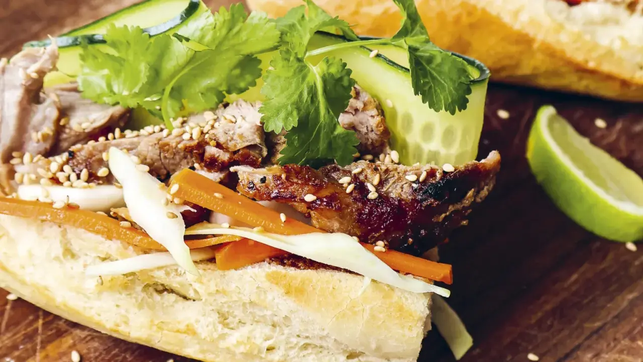 En saftig banh mi med grillat kött, krispiga grönsaker och sesamfrön. Ett perfekt banh mi recept för en smakrik lunch.