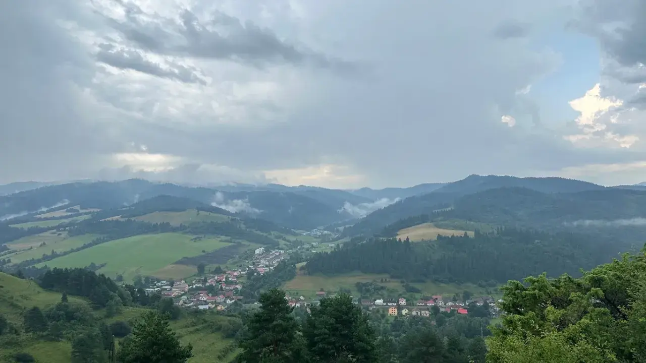 Widok na dolinę z wioską i górami w tle, chmury nad przełęczą pod Tokarnią.