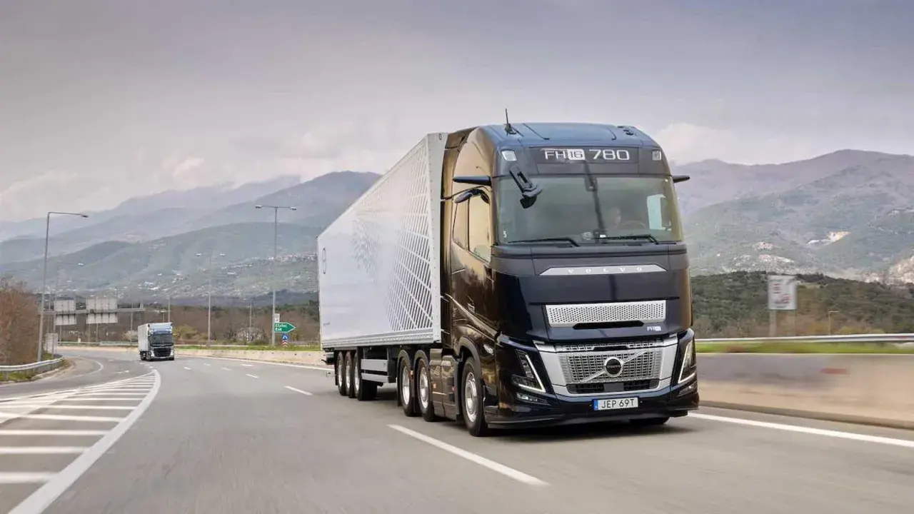 Camión Volvo FH Aero 780 negro con remolque blanco avanza por una carretera montañosa.