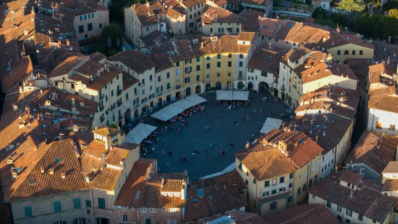 Vista aerea di Piazza dell'Anfiteatro a Lucca, perfetta per un weekend indimenticabile tra tetti rossi e vita cittadina.