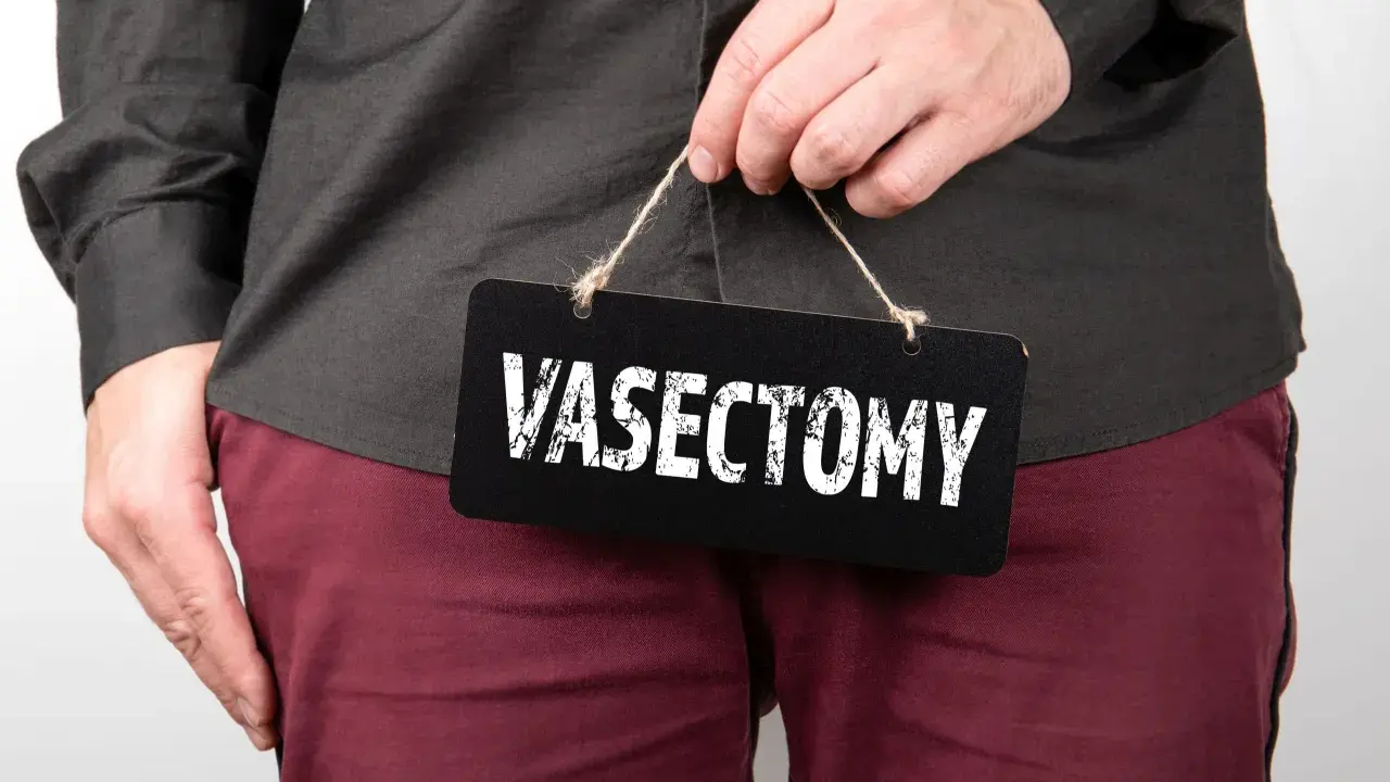 Mężczyzna trzyma tabliczkę z napisem "VASECTOMY". Czy po wazektomii można mieć dzieci? To pytanie nurtuje wielu.