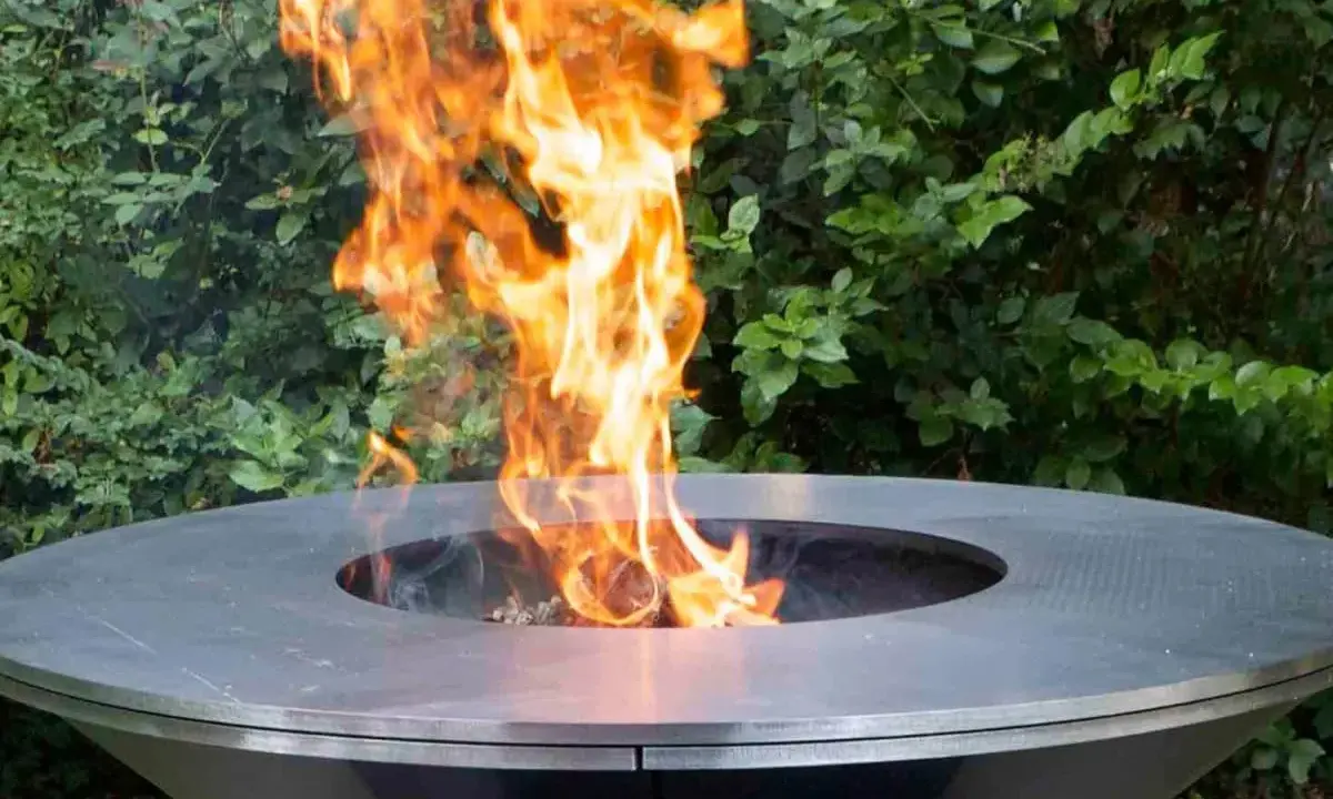 Un moderno braciere da giardino, con fiamme vivaci che danzano al centro, crea un'atmosfera accogliente.