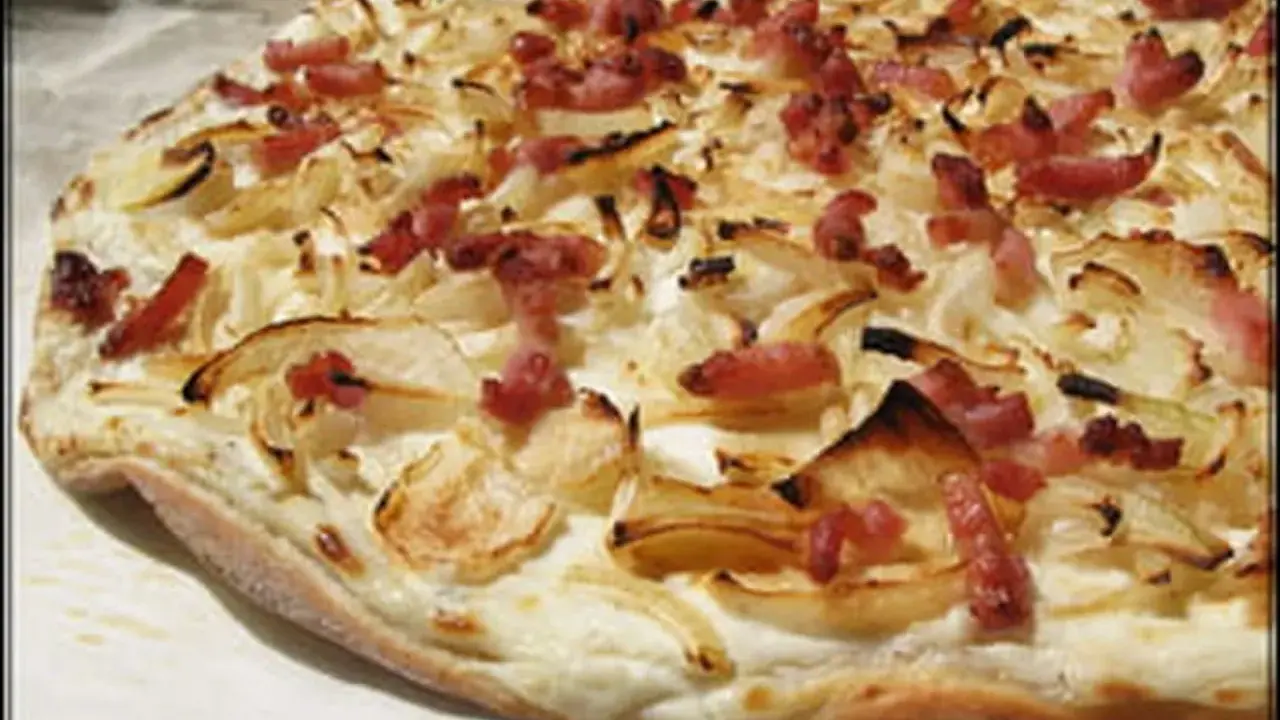 Flammekueche croustillante, garnie d'oignons et de lardons. Une recette facile pour un plat savoureux.