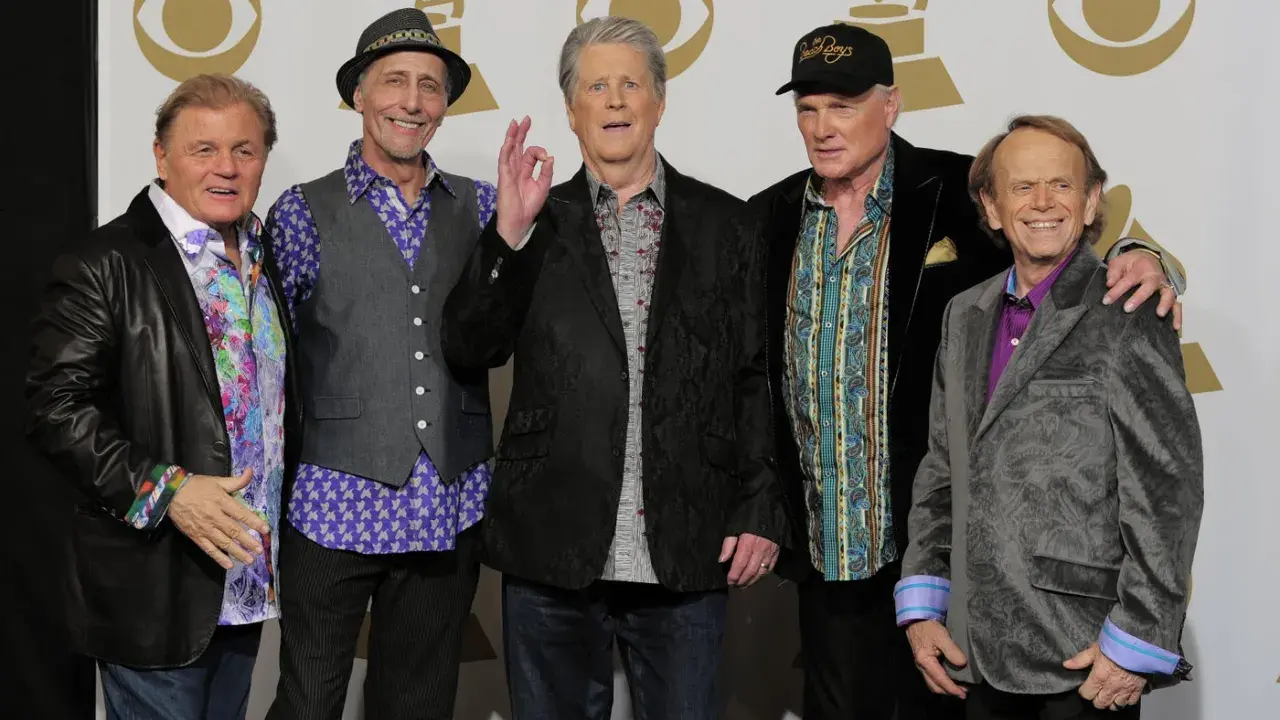 Fem leende medlemmar av The Beach Boys poserar för ett foto.