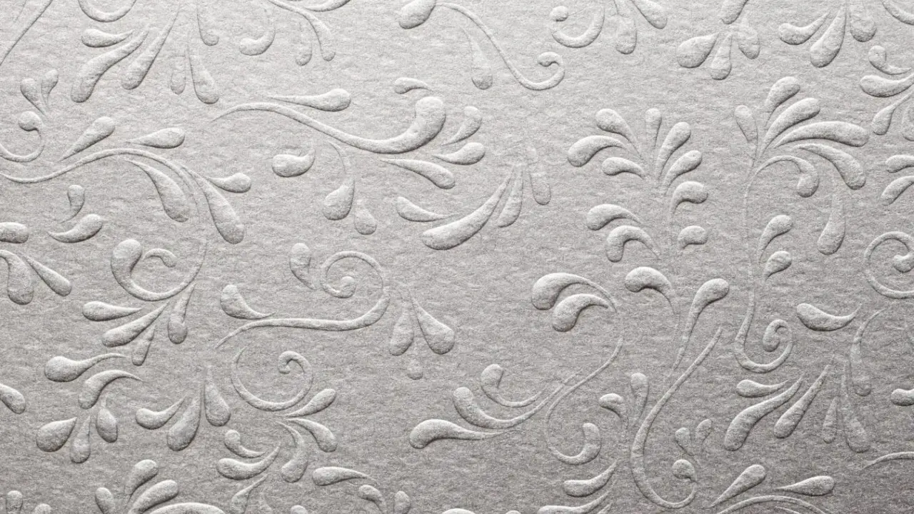 Srebrzyste, wytłaczane wzory roślinne na papierze, przypominające eleganckie uszlachetnienia druku.