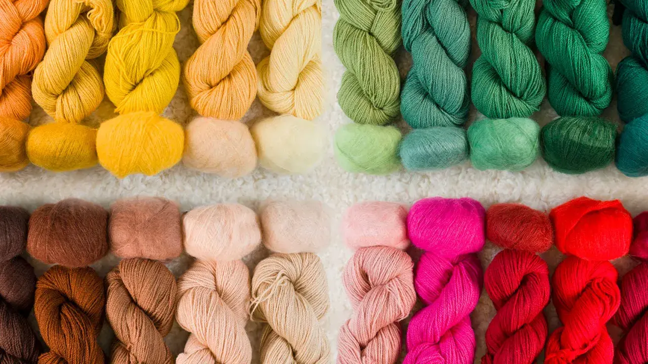 Ett urval av garn i olika färger, från varma orange och gula toner till gröna, rosa och röda nyanser. Perfekt för ditt nästa projekt med garn lin.