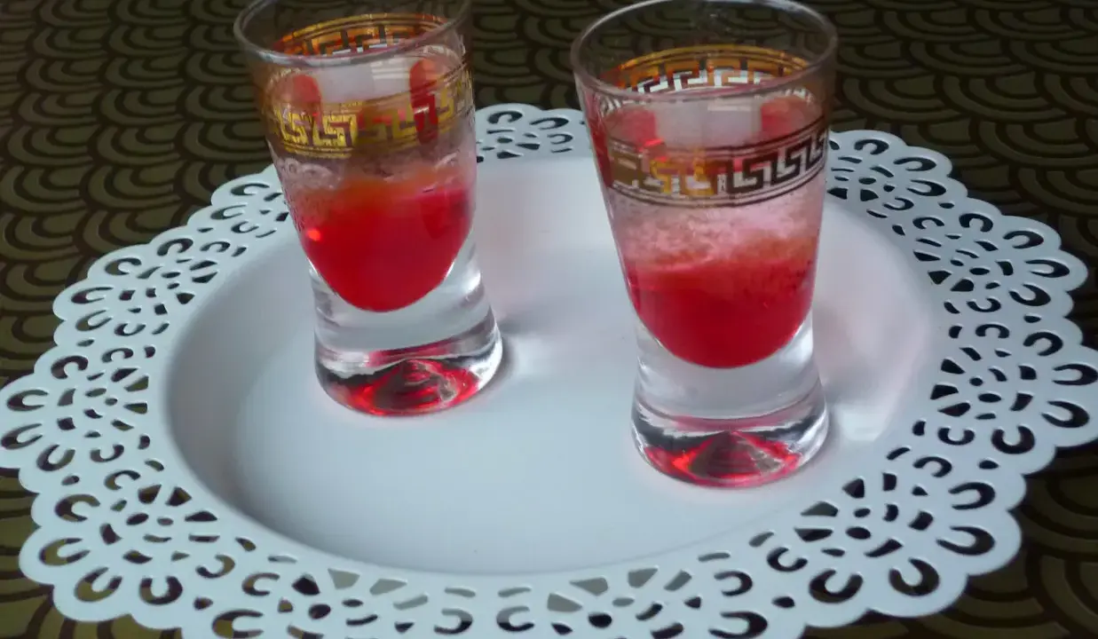 Dwa kieliszki z czerwonym drinkiem, ozdobione złotym wzorem. Wyglądają jakby miały moc, niczym wściekły pies drink.