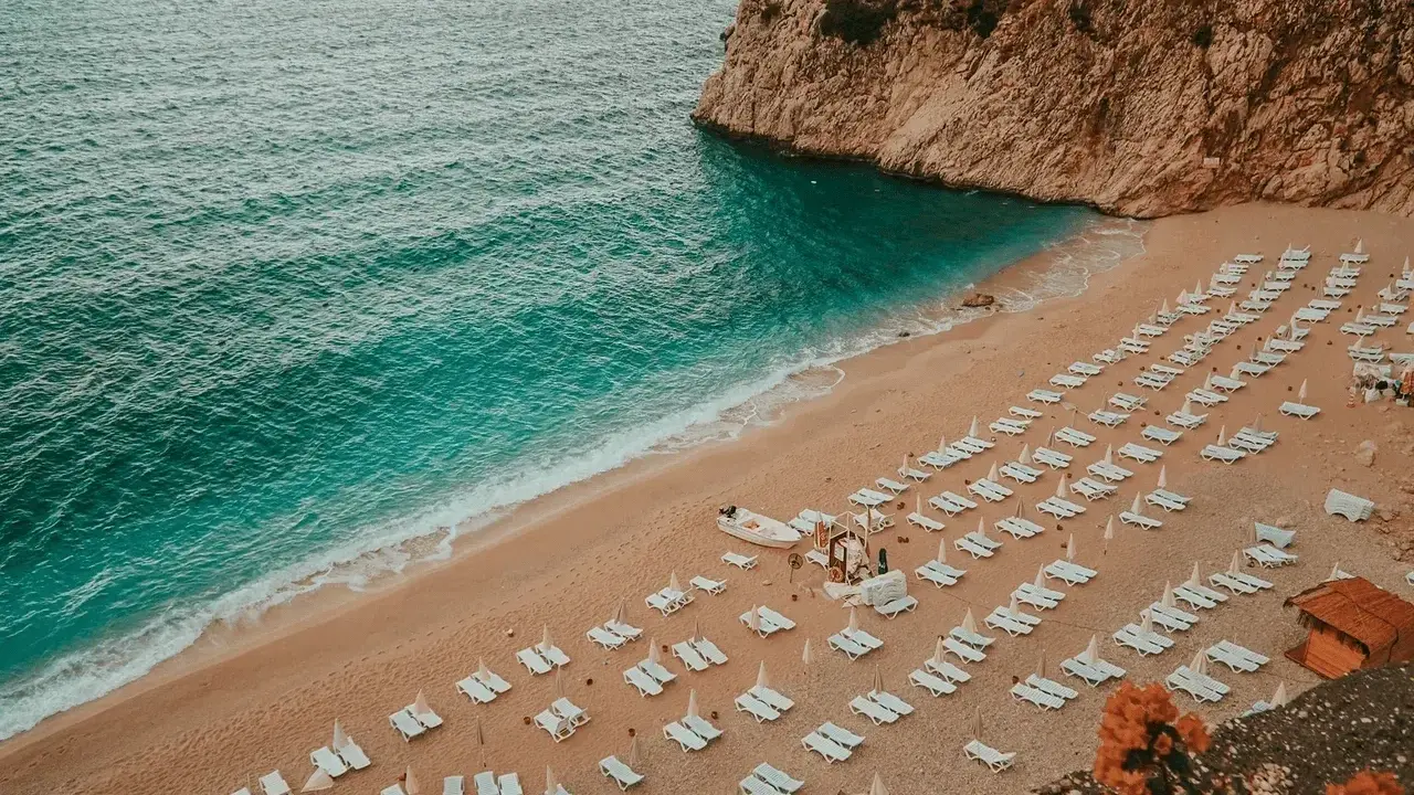 Piękna plaża z rzędami leżaków i turkusową wodą. Idealne miejsce, gdzie do Turcji na wakacje.