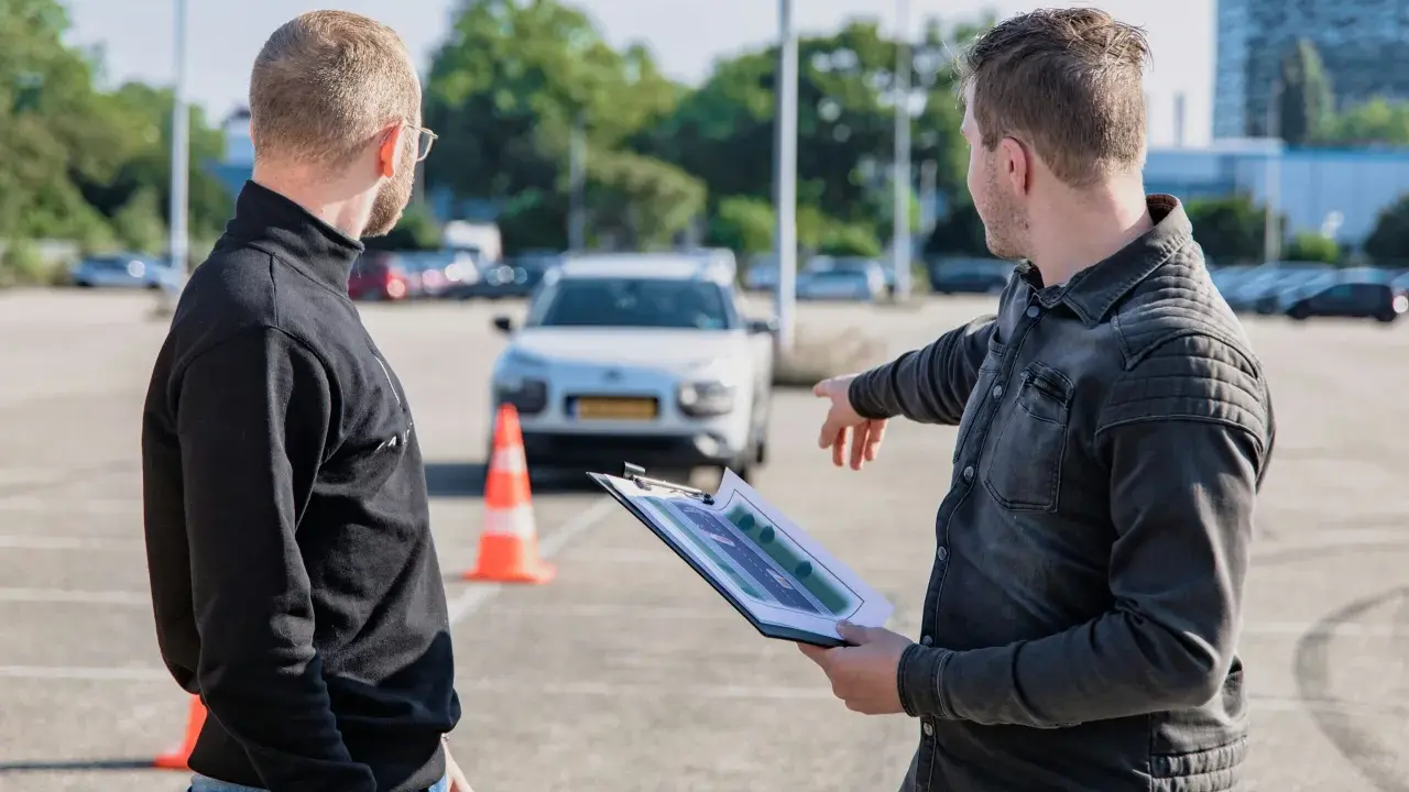 Instruktor omawia z kursantem plan trasy, świętując jego pozytywny wynik egzaminu teoretycznego.