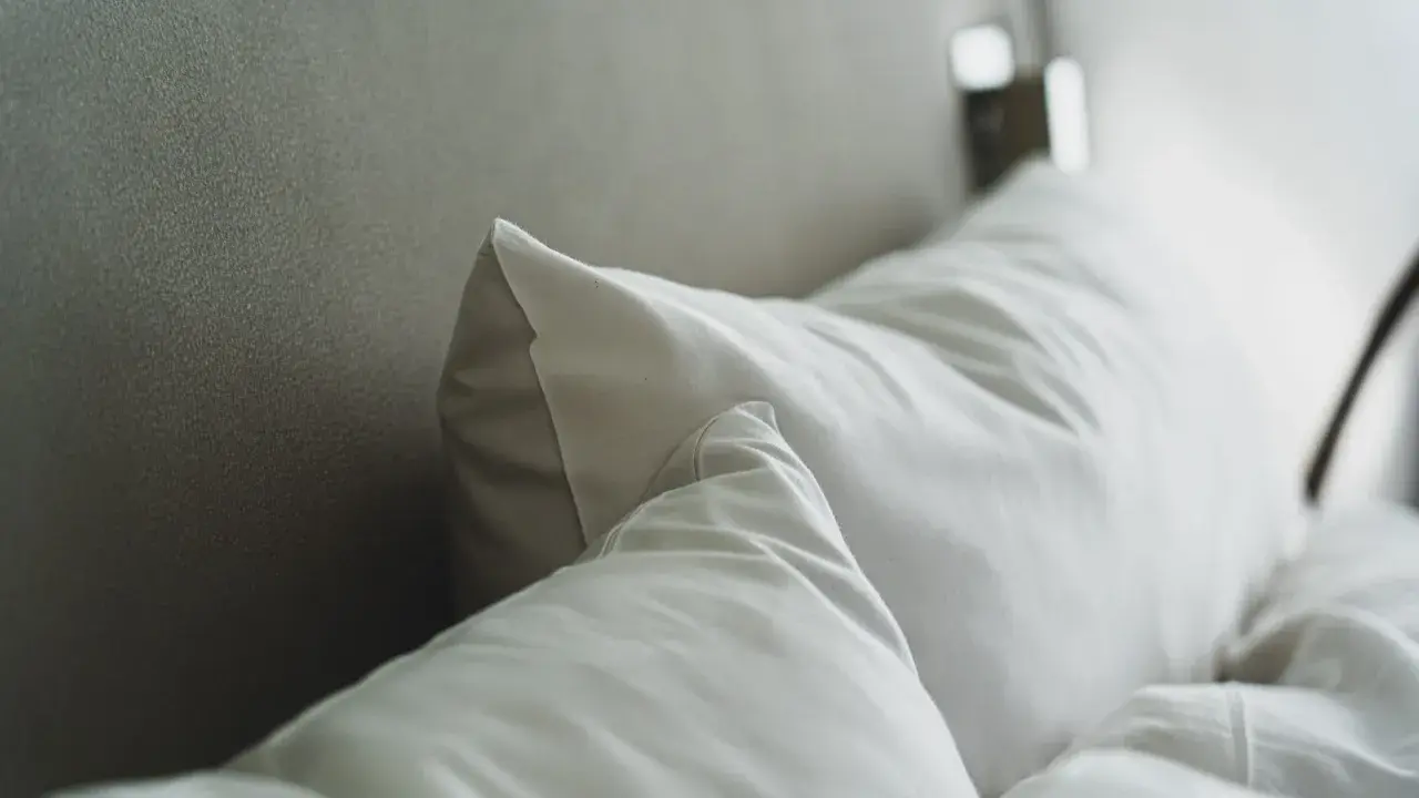 Cojines blancos sobre una cama, perfectos para conocer las medidas de cojines para cama de 150.