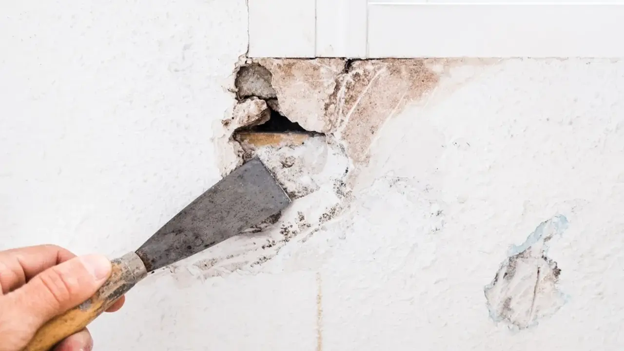 Mano con espátula preparando una pared para tapar agujeros.