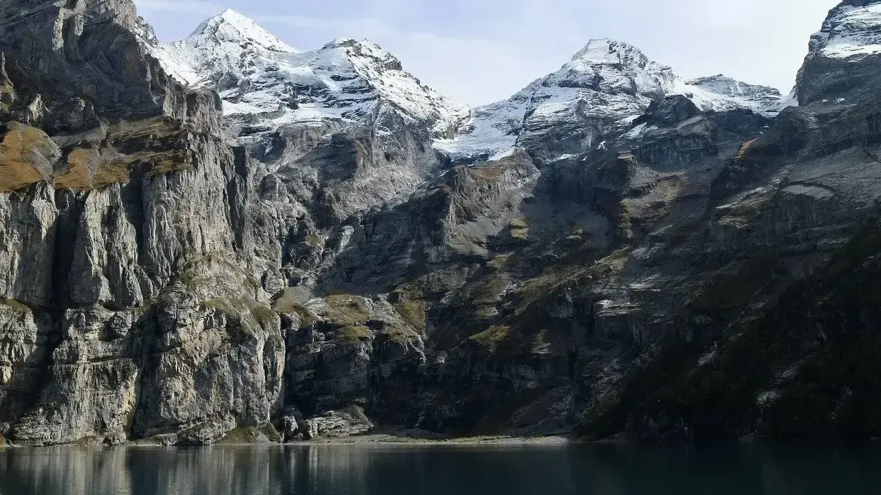 Majestatyczne Tatry Wschodnie z ośnieżonymi szczytami odbijają się w spokojnej tafli jeziora.