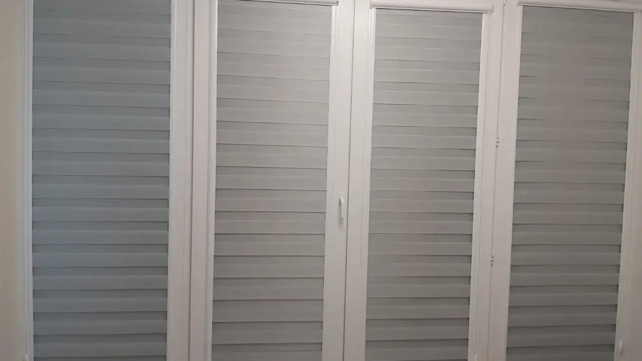 Nowoczesne rolety dzień i noc w odcieniach szarości na drzwiach balkonowych. Czy do rolet dzień i noc pasują firanki? To zależy od stylu wnętrza.