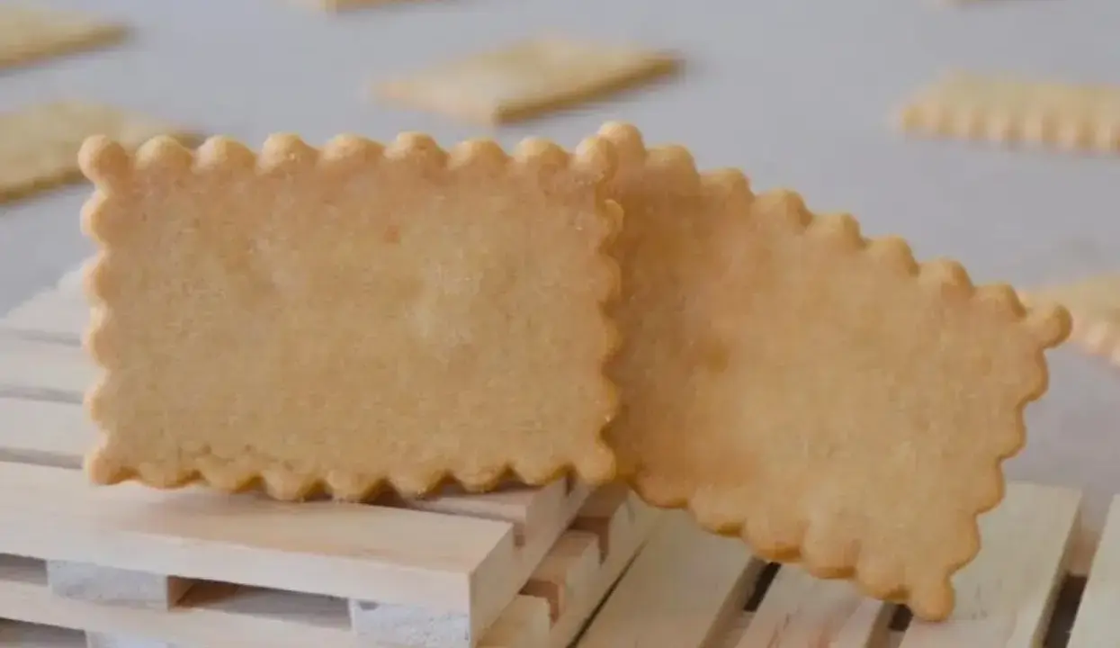 Deux biscuits rectangulaires aux bords festonnés, parfaits pour une recette biscuit personnalisé. Ils reposent sur des petites palettes en bois.