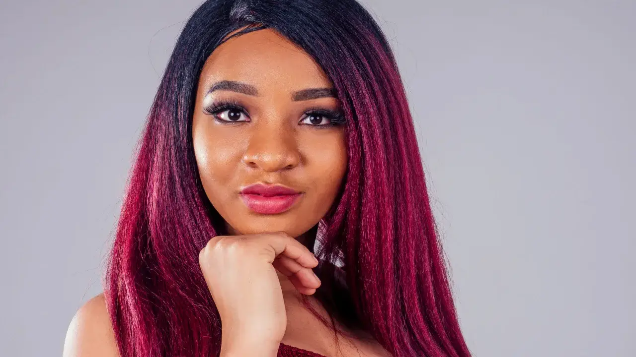 Una giovane donna con capelli color prugna, un look audace che le sta benissimo.