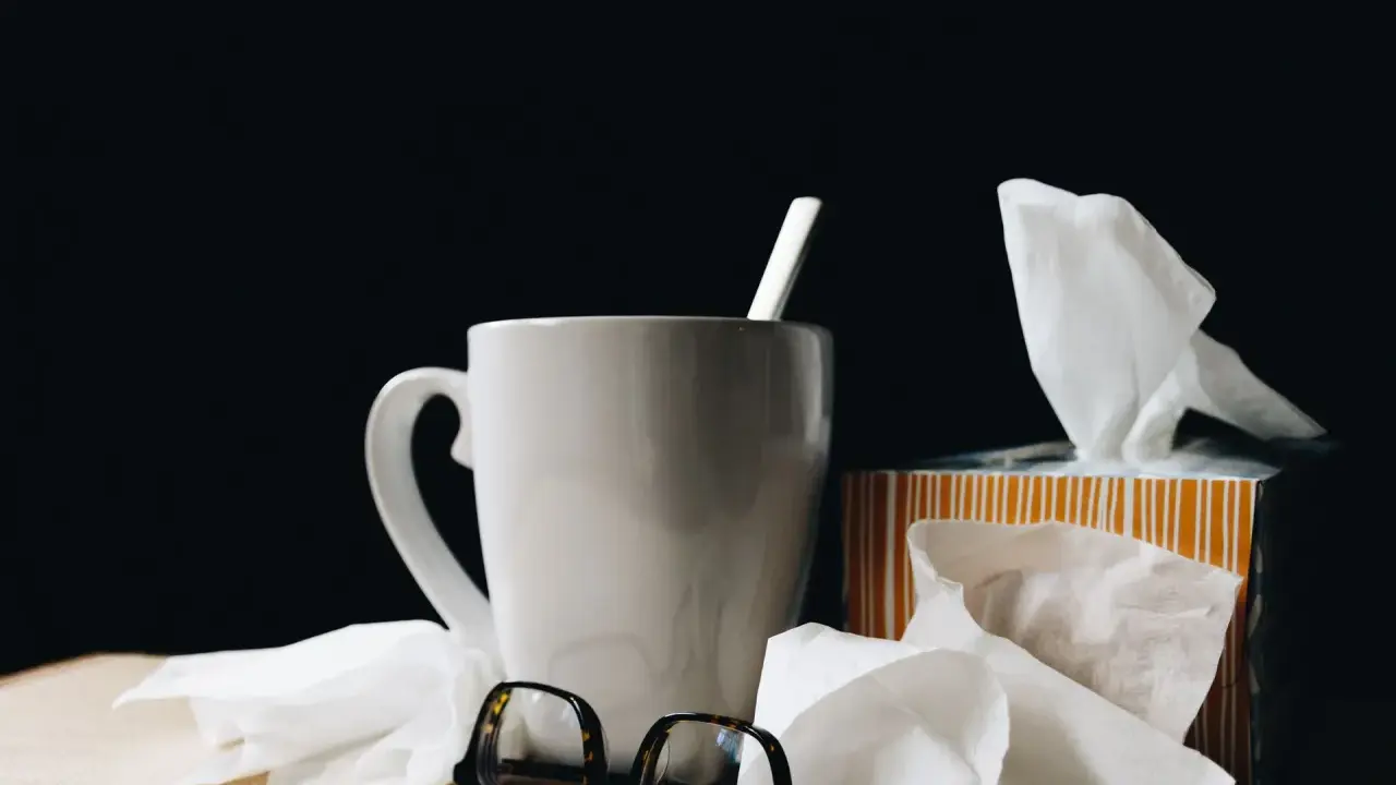 Kubek z herbatą, chusteczki i okulary. Urlop L4 nie zawsze jest wypoczynkiem.