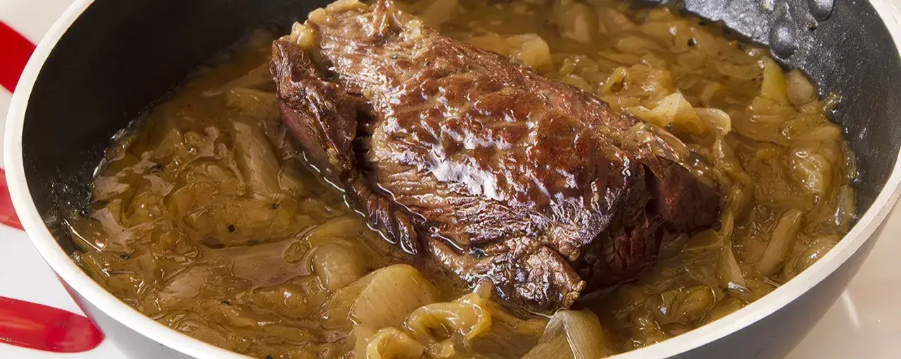 Une succulente buche d'onglet mijote dans une sauce aux oignons caramélisés, prête à être dégustée.