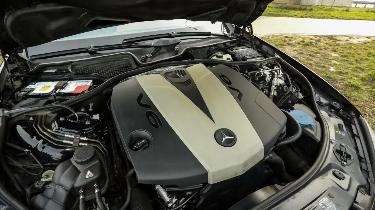 Silnik V6 om642 Mercedesa z otwartą maską. Widoczny akumulator, płyny i elementy osprzętu.