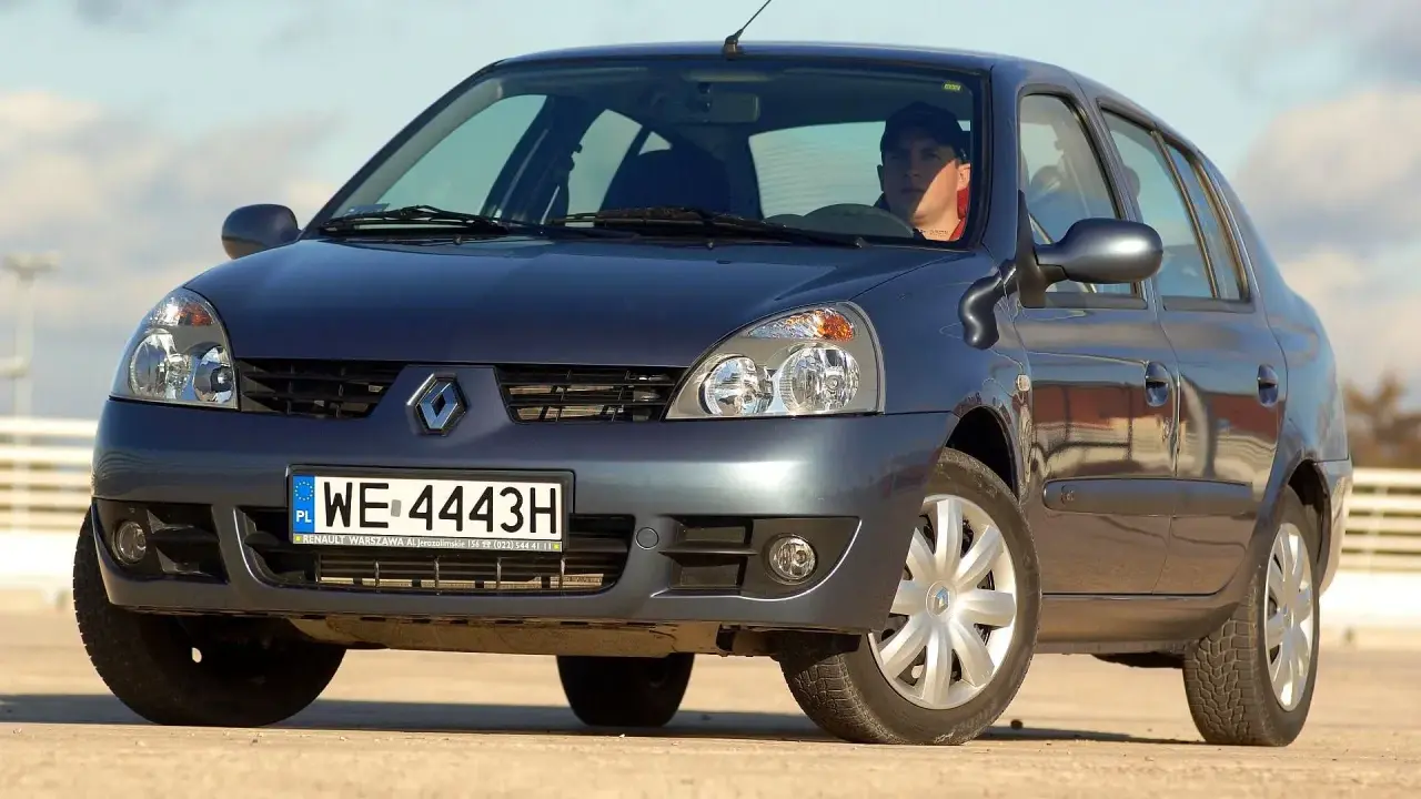 Ciemnogranatowy Renault Thalia 1.4 z kierowcą za kierownicą, zaparkowany na zewnątrz.