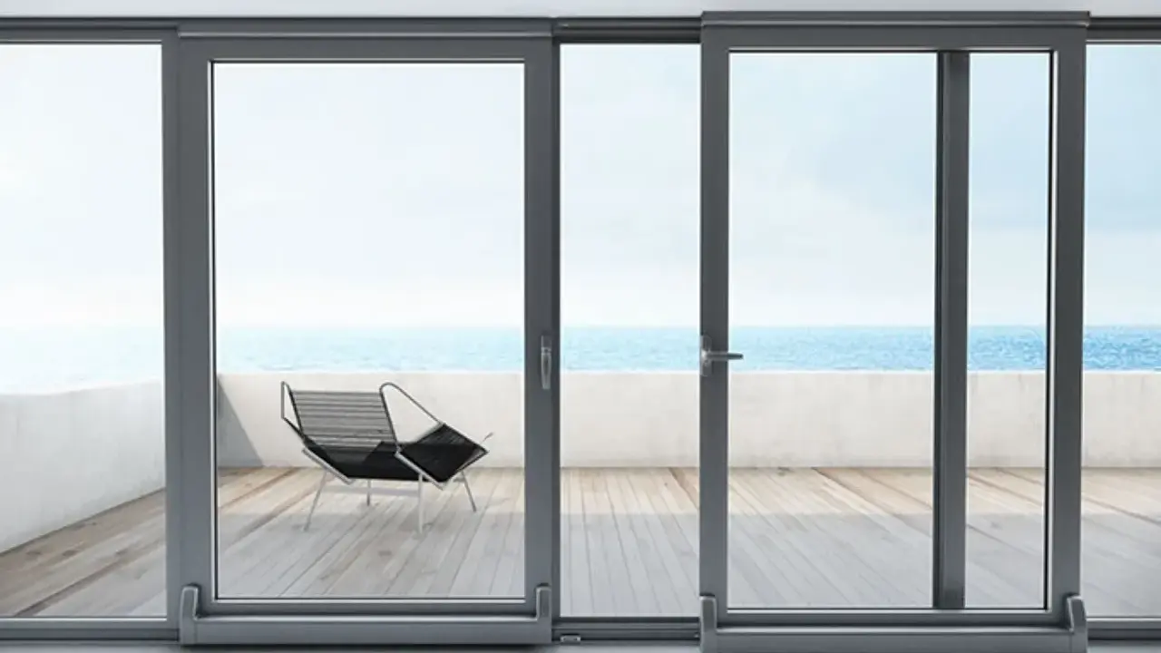 Ventanas osciloparalelas con vista al mar. Un sillón moderno en la terraza de madera.