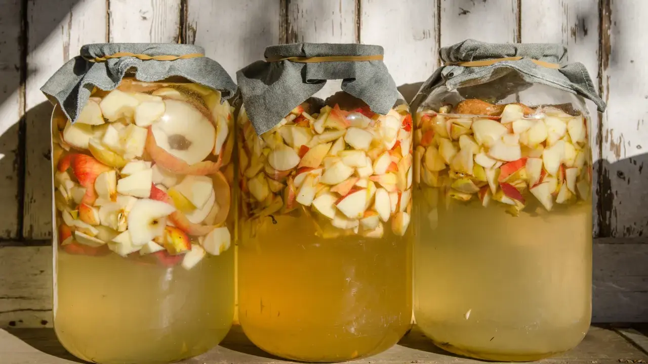 Trois bocaux remplis de pommes coupées, prêts pour la vinaigre de cidre recette de grand-mère.