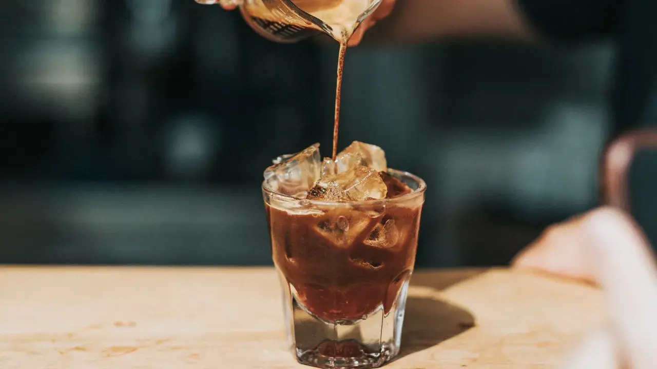 Ein Espresso fließt in ein Glas mit Eiswürfeln. Ist kalter Kaffee gesund? Diese Erfrischung könnte eine Antwort sein.