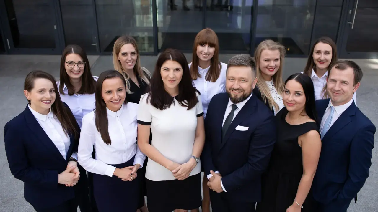 Grupa prawników w garniturach i strojach biznesowych pozuje przed budynkiem.