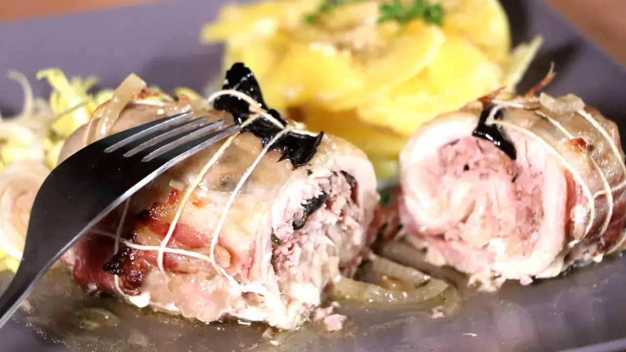 Une cuisse de poulet farcie, savoureusement roulée et ficelée, attend d'être dégustée avec une garniture de pommes de terre.