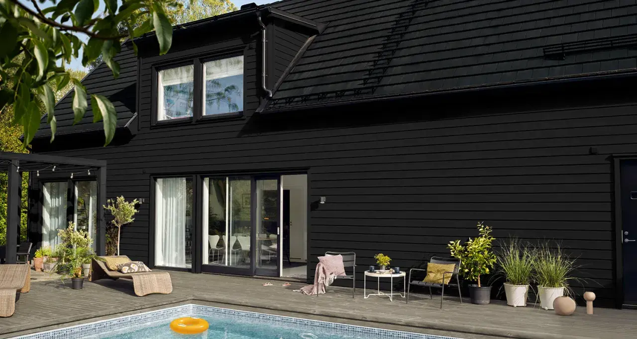 Ett modernt svart hus med pool och uteplats. Perfekt för att måla i solsken och njuta av sommaren.