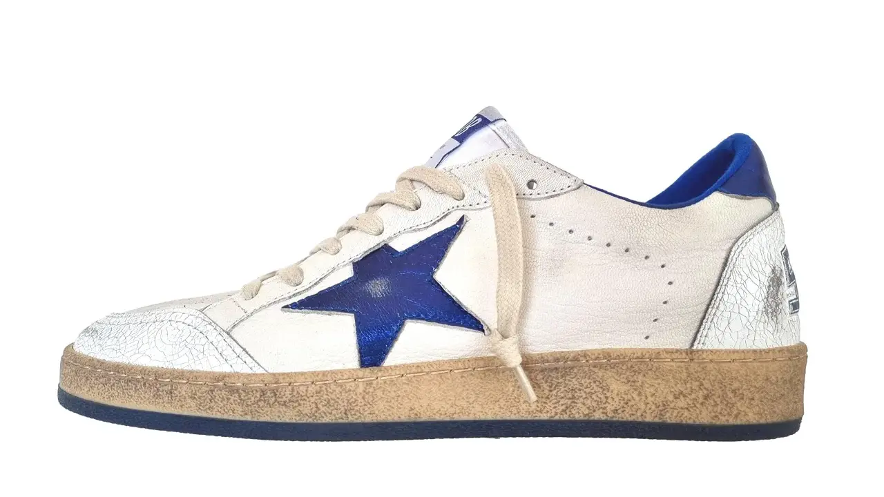 Białe sneakersy z niebieską gwiazdką, znane jako buty z gwiazdką, mają przetarty wygląd i niebieskie detale.