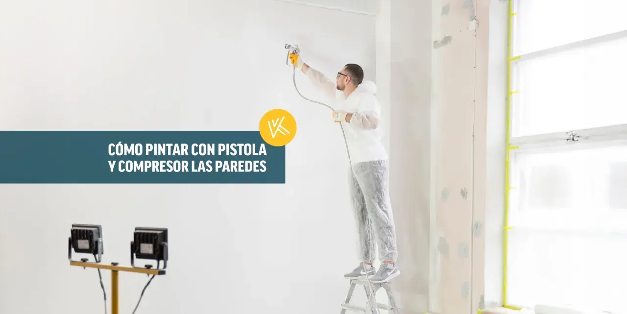 Hombre con traje protector pintando una pared con pistola y compresor.
