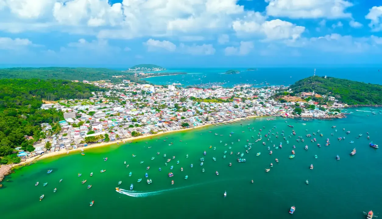 Luftaufnahme einer Küstenstadt mit vielen Booten im türkisfarbenen Meer. Perfekt für die phu quoc beste reisezeit.