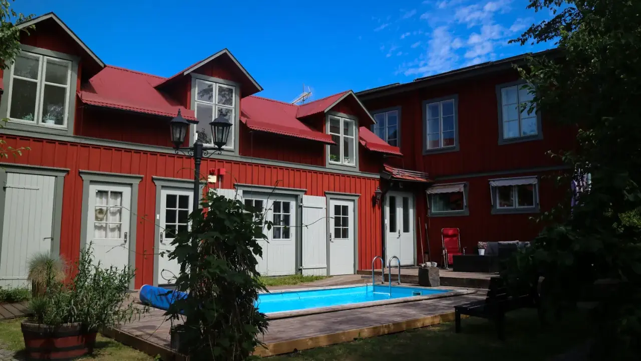 Rött hus med vita fönsterluckor och en blå pool. Kanske finns det tre små rum därinne, redo för gäster.