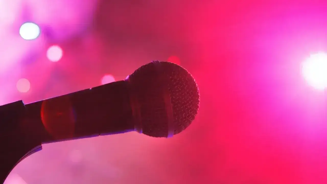 Mikrofon na scenie, otoczony różowym światłem. Czas na śpiewanie bez słów, tylko czyste emocje.