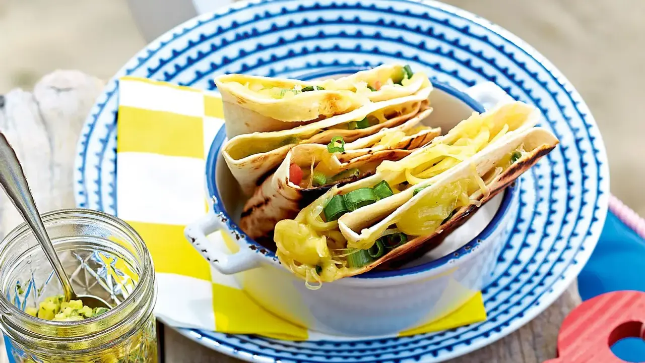 Leckeres Quesadillas Rezept: goldbraune Tortillas gefüllt mit geschmolzenem Käse und Frühlingszwiebeln, serviert in einer Schüssel.