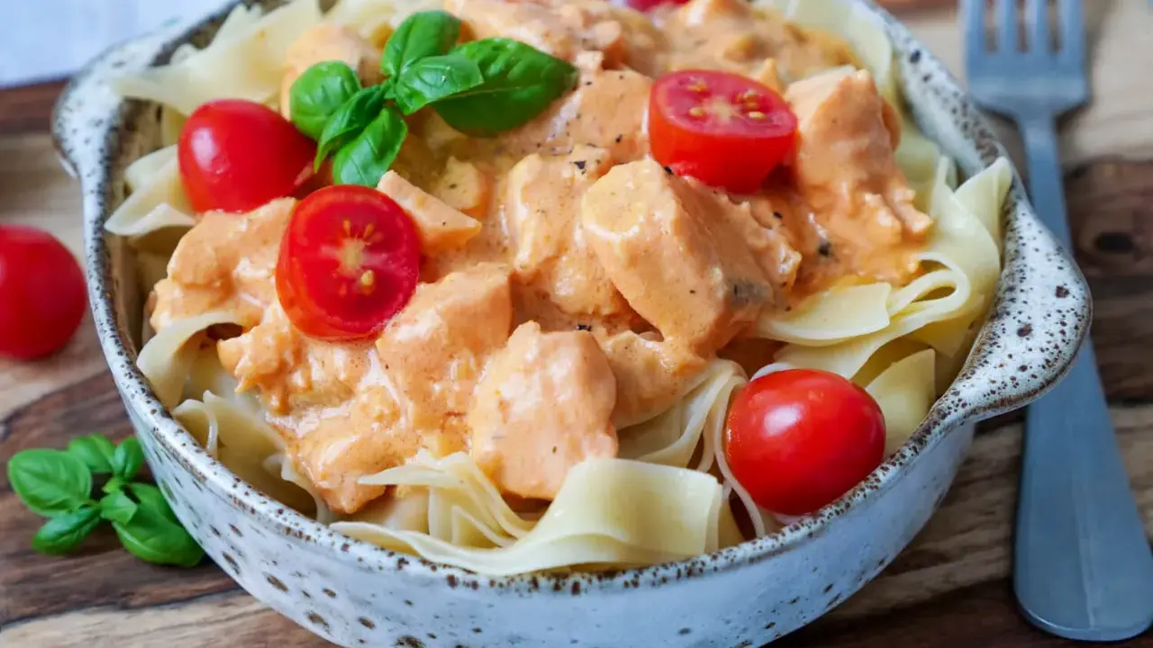 Schmackhafte Nudeln mit Lachs in cremiger Sauce, garniert mit Kirschtomaten und Basilikum. Ein Genuss!