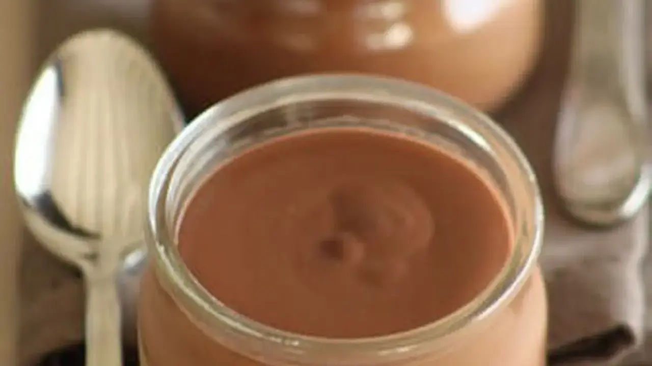 Un pot de crème chocolat onctueuse, prêt à être dégusté avec une cuillère.