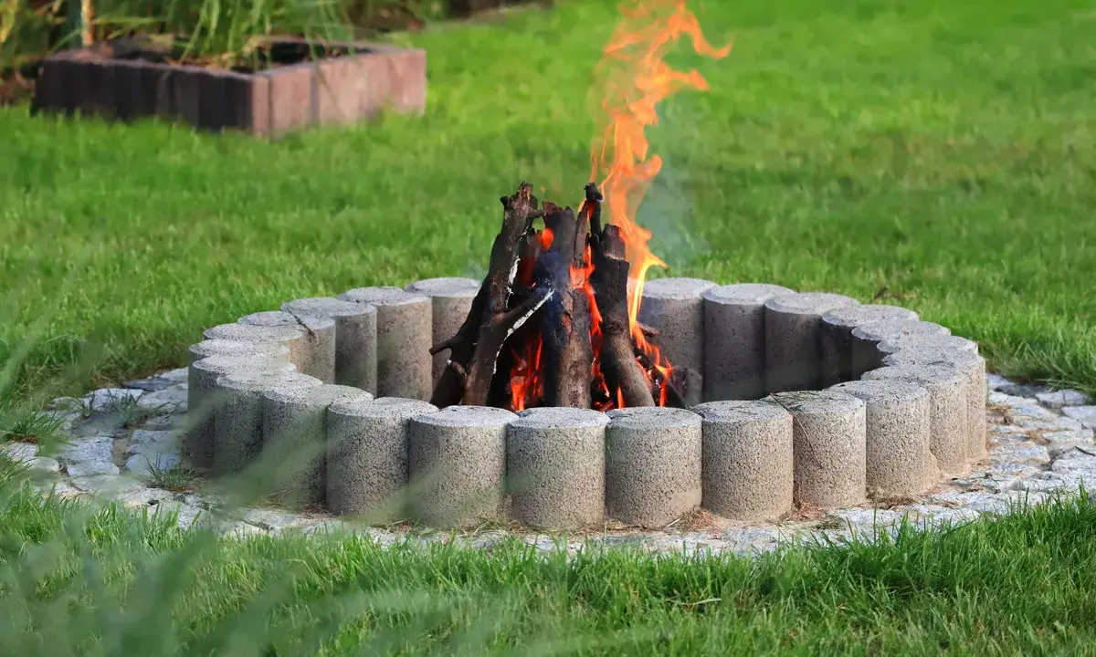Eine Feuerstelle mit gemauerten Steinen und loderndem Feuer im Garten.