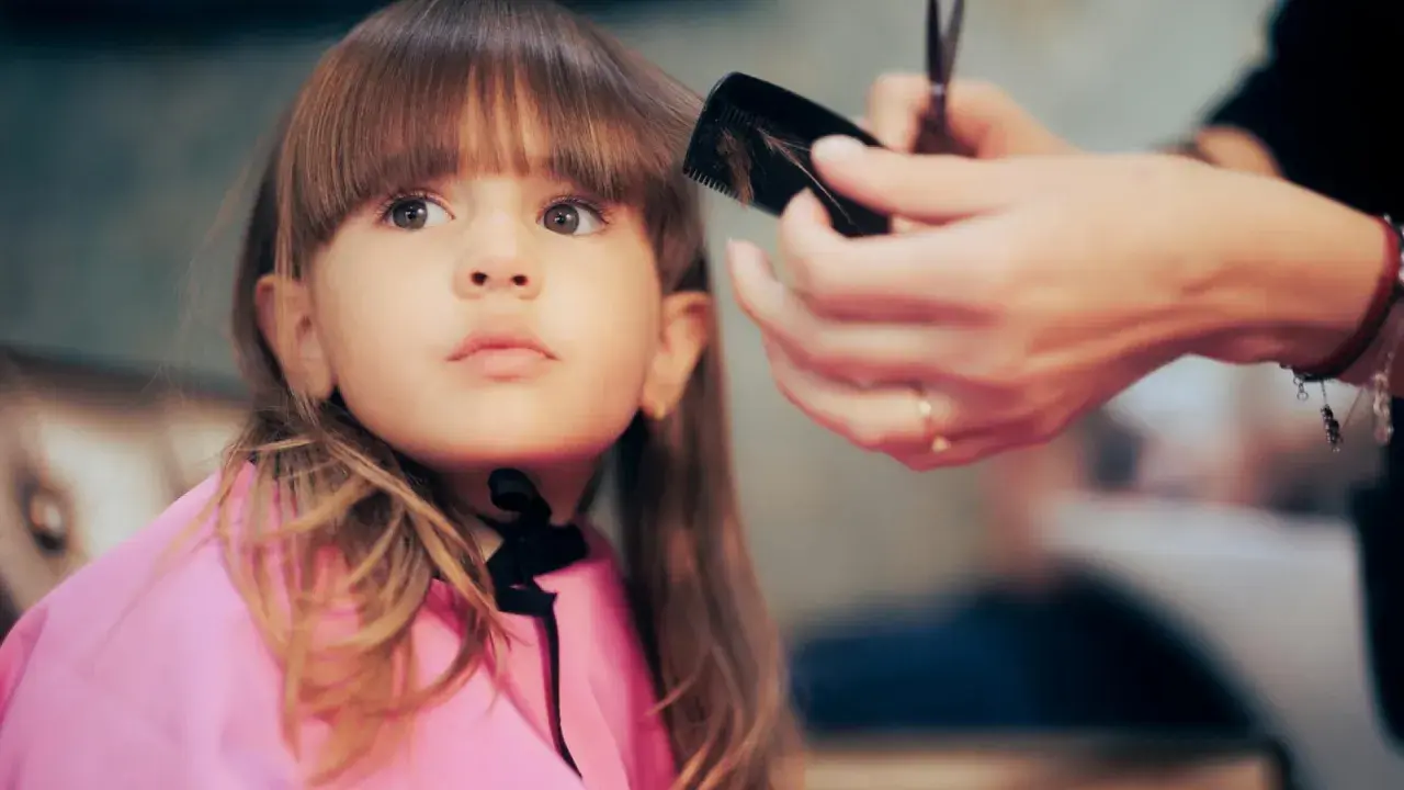 Ein **Kind** bekommt einen neuen **Pony schneiden** im Friseursalon.