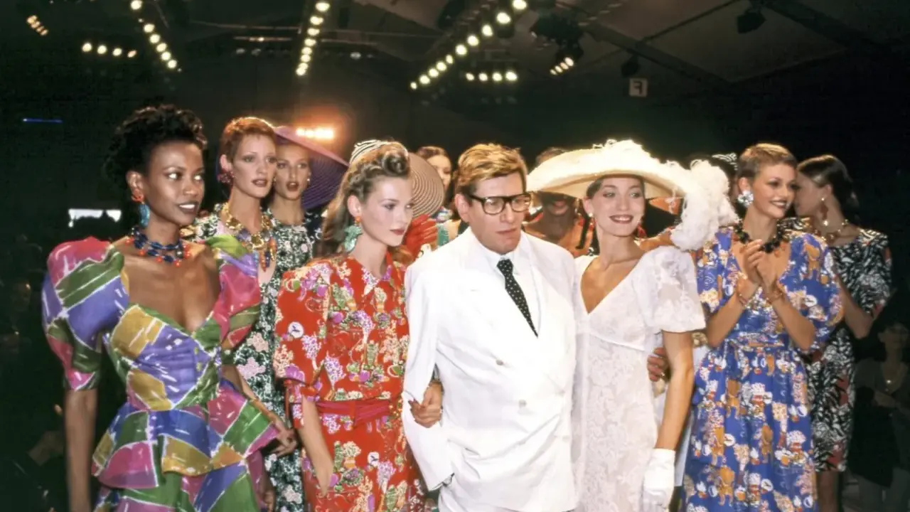 Models and designer Yves Saint Laurent at the Staley Wise Gallery fashion show, showcasing vibrant, patterned dresses and bold accessories.