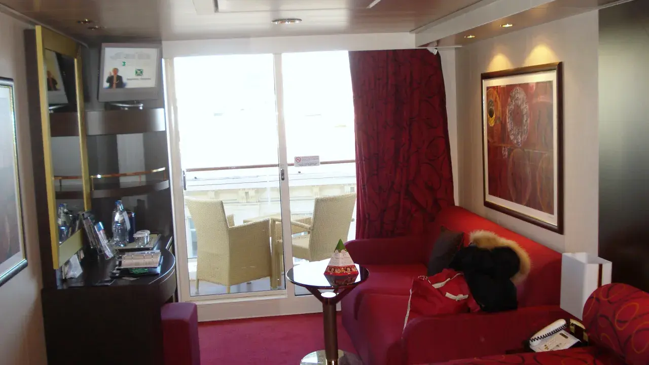 Cabina su MSC Divina, ponte 9, con balcone, divano rosso, letto e quadro astratto.