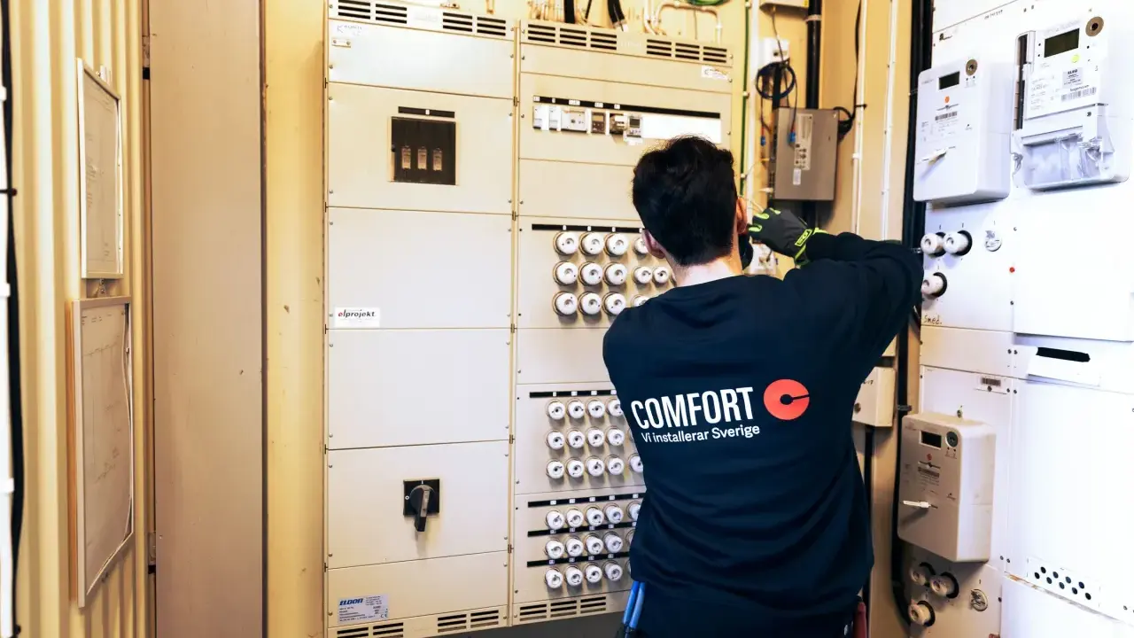 En elektriker arbetar vid en elcentral med många säkringar och mätare. För säkerheten måste man ha jordfelsbrytare.