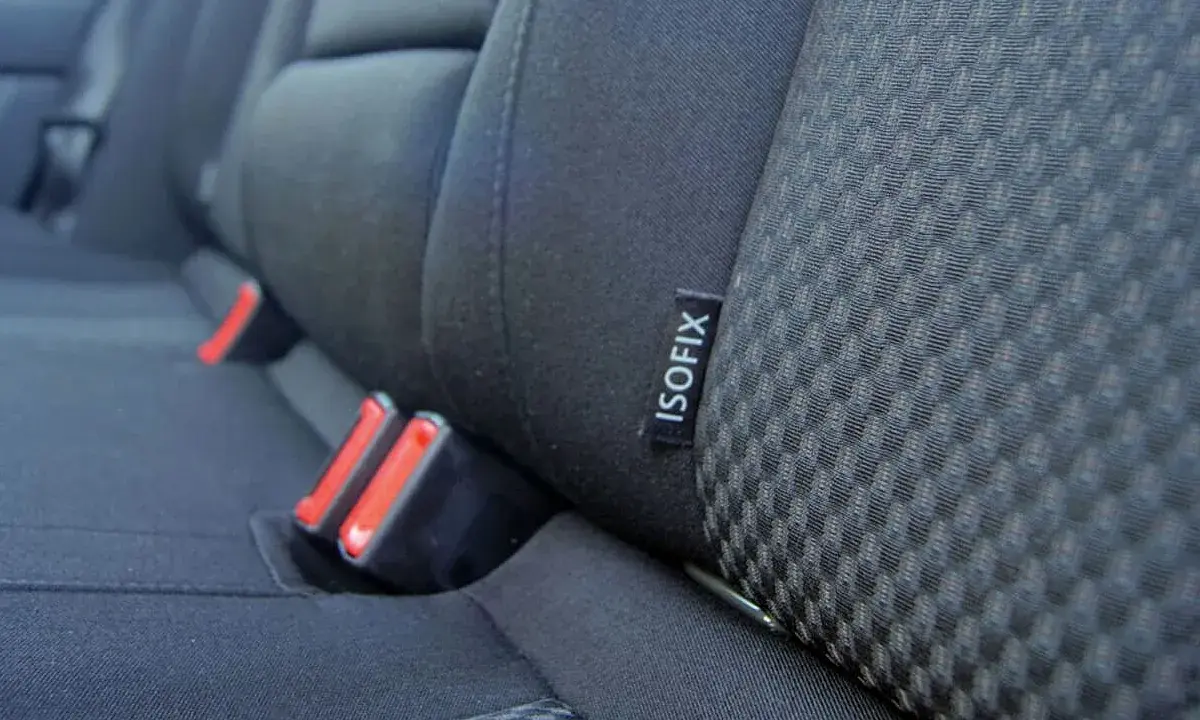 Etiqueta negra con el **símbolo ISOFIX** en el asiento de un coche, junto a los anclajes de seguridad.
