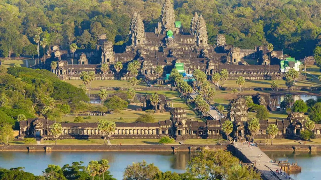 Majestatyczna świątynia Angkor Wat w Siem Reap, otoczona bujną zielenią, z mostem i jeziorem w tle.