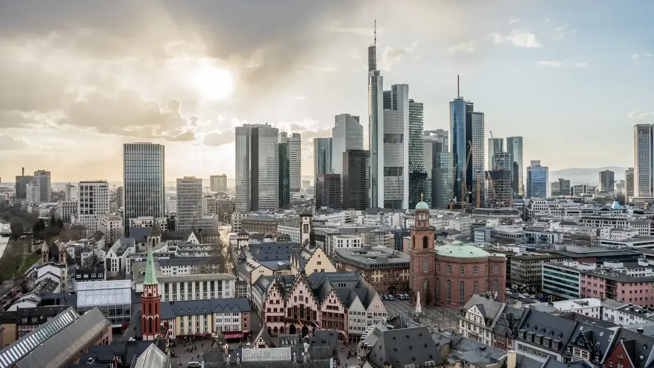 Widok na nowoczesne i zabytkowe frankfurt nad menem dzielnice, z drapaczami chmur i kościołami pod zachodzącym słońcem.