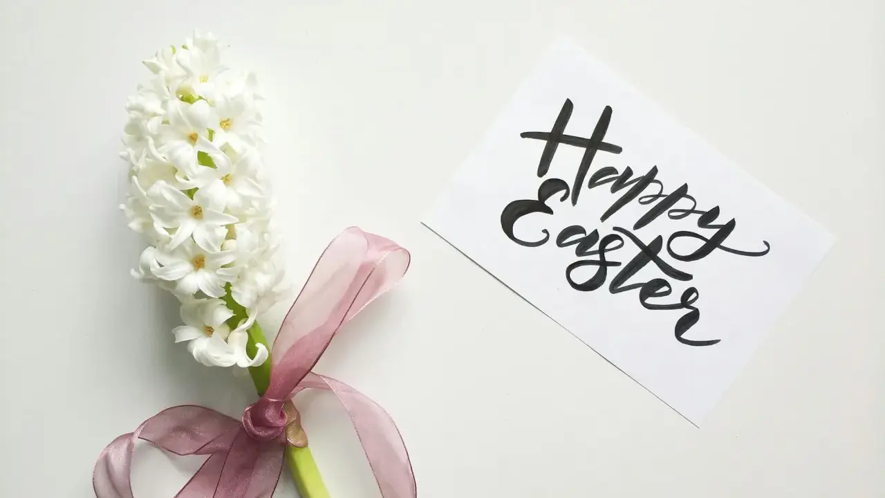 Un giacinto bianco legato con un nastro rosa, accanto a un biglietto con scritto "Happy Easter". Come una poesia campane di Pasqua di Gianni Rodari.