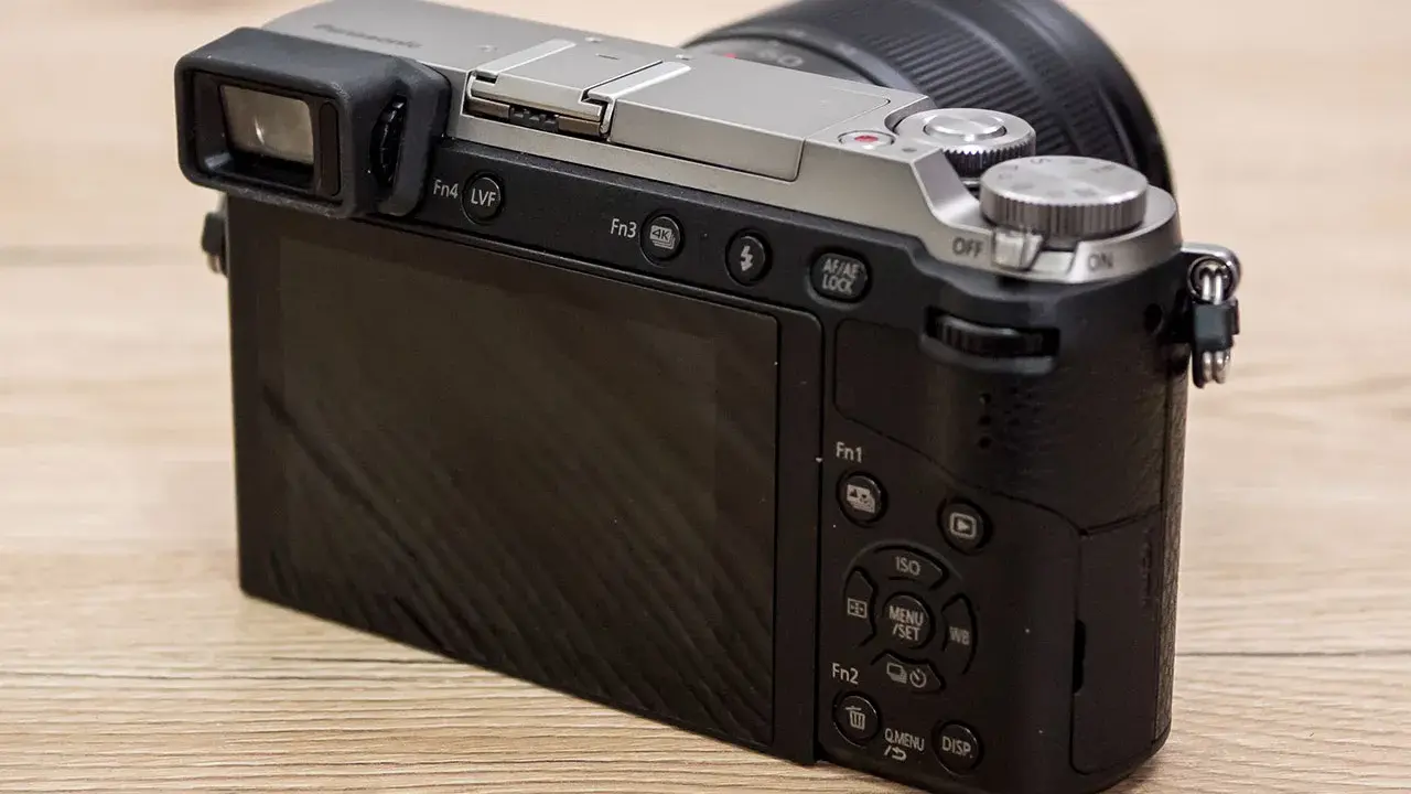 Retro della fotocamera Panasonic Lumix GX80 con obiettivo. Schermo LCD e mirino elettronico visibili.